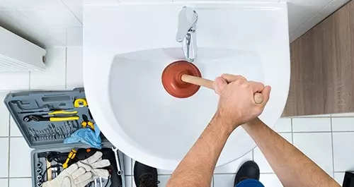 plumber unblocking a sink drain